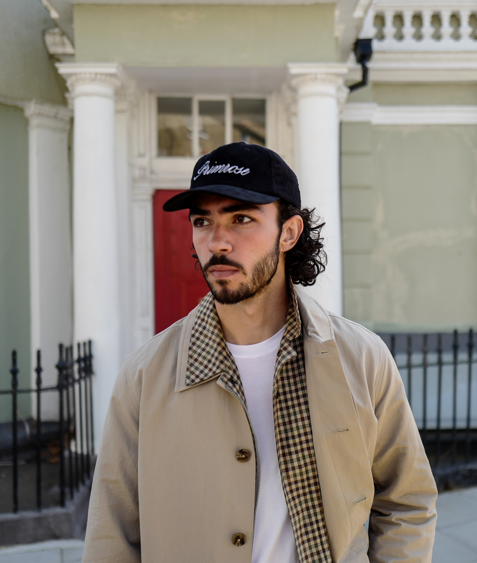 Man wearing a black cap with 'Amoske' logo in front of a building with white columns.