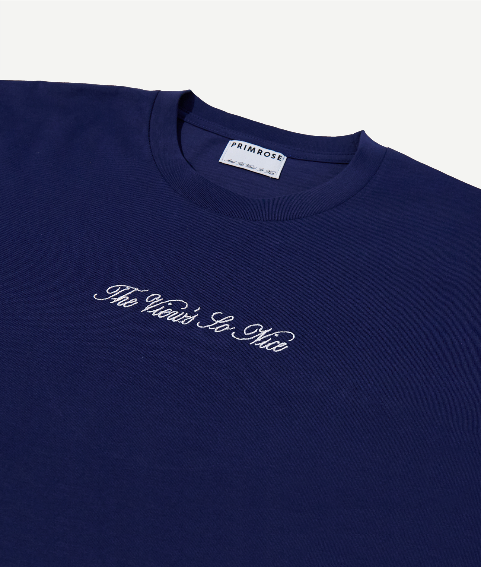 Navy blue t-shirt with white text and 'PRIMROSE' label on a light gray background