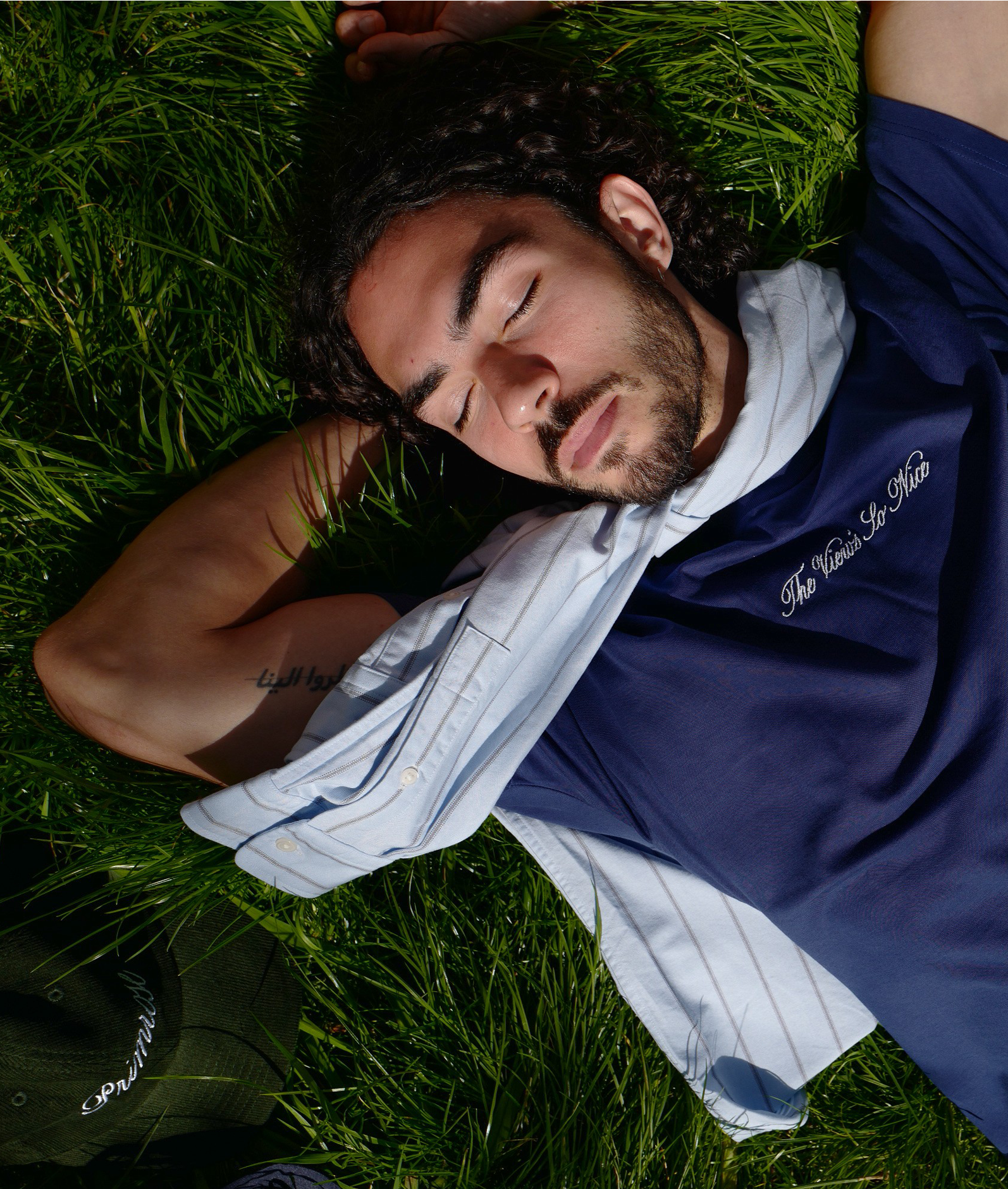 Man lying on grass wearing a blue shirt with text