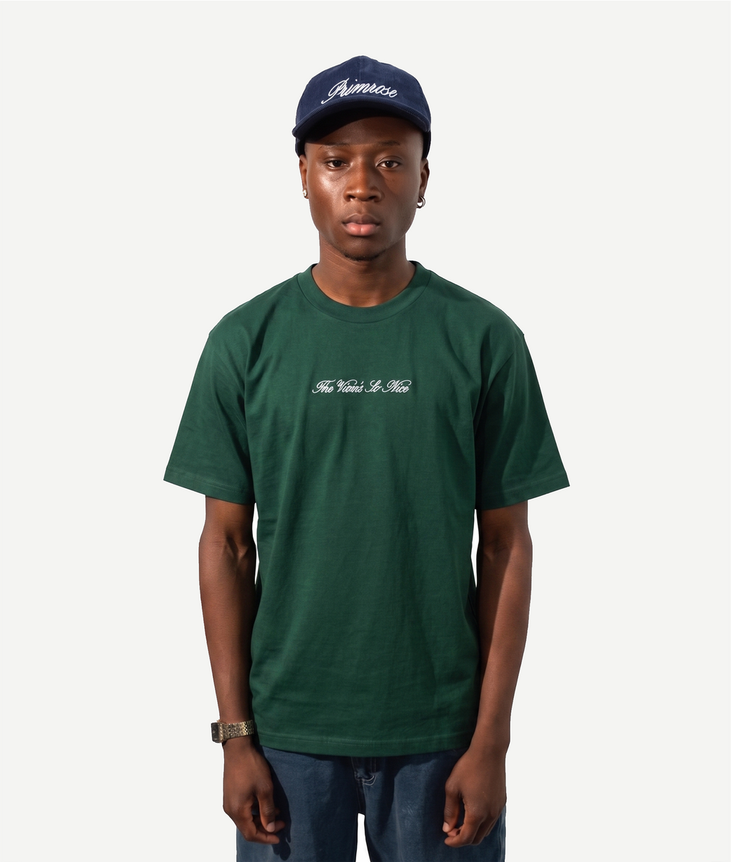 Person wearing a green t-shirt and navy cap on a white background embroidered with The View's So Nice