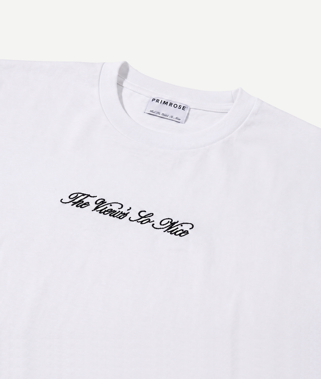 White t-shirt with black text 'The World is So Nice' and 'PRIMROSE' label on a white background