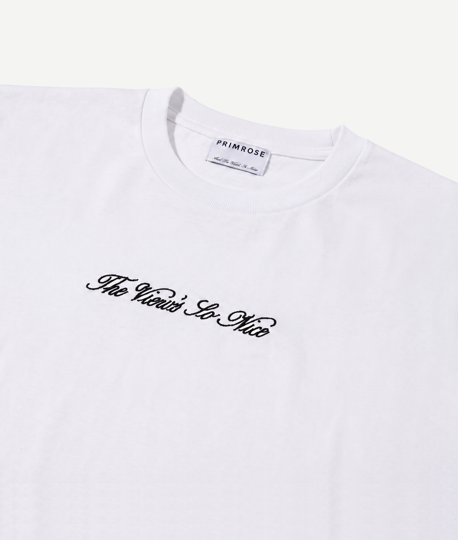 White t-shirt with black text 'The World is So Nice' and 'PRIMROSE' label on a white background