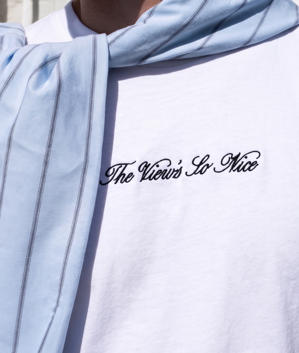 Light blue scarf draped over a white shirt with 'The View's So Nice' text.